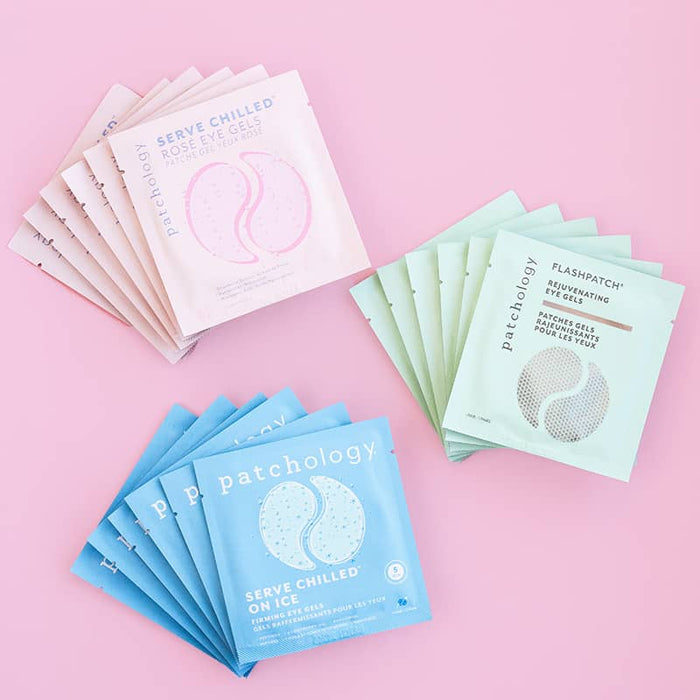 Stacks of Patchology eye mask packets on a pink background