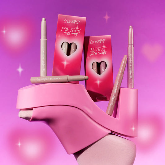 ColourPop All Eyes On Me Shadow Stix Set from the Heart to Get collection balanced on a bright pink platform heel, showing multiple nude-toned shadow sticks and heart-cutout boxes against a dreamy pink gradient background with sparkles.