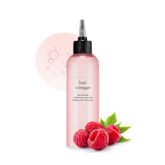 A pink bottle labeled 'hair vinegar' with a black cap and white text, branded as A'pieu. With raspberries next to it.