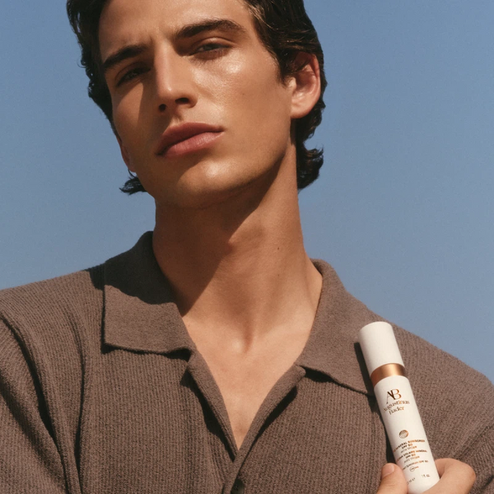 Man holding Augustinus Bader The Mineral Sunscreen SPF 50 bottle on his shoulder
