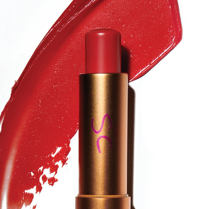 Augustinus Bader The Tinted Balm in gold and red, shown with a sheer red lip swatch