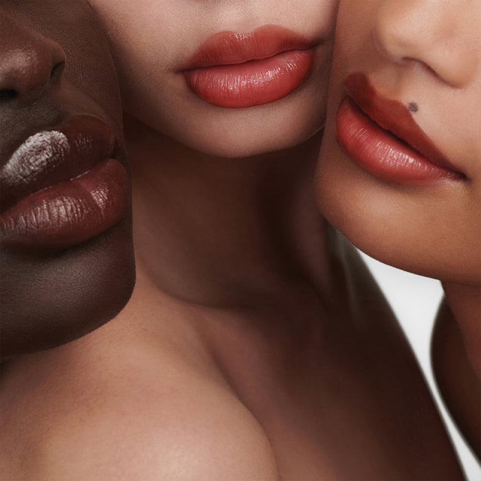 Three models’ lips wearing sheer tinted balm in rosy nude shades
