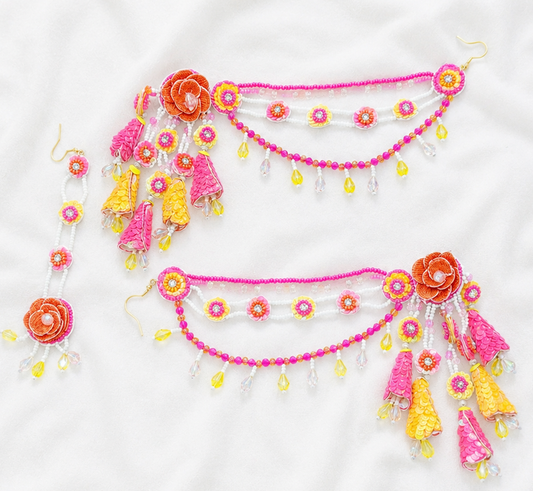 A pair of traditional Indian beaded waist chains (Bangles) with matching dangling earrings, decorated with vibrant pink, orange, and yellow beads, sequins, and tassels, laid flat on a white fabric background.