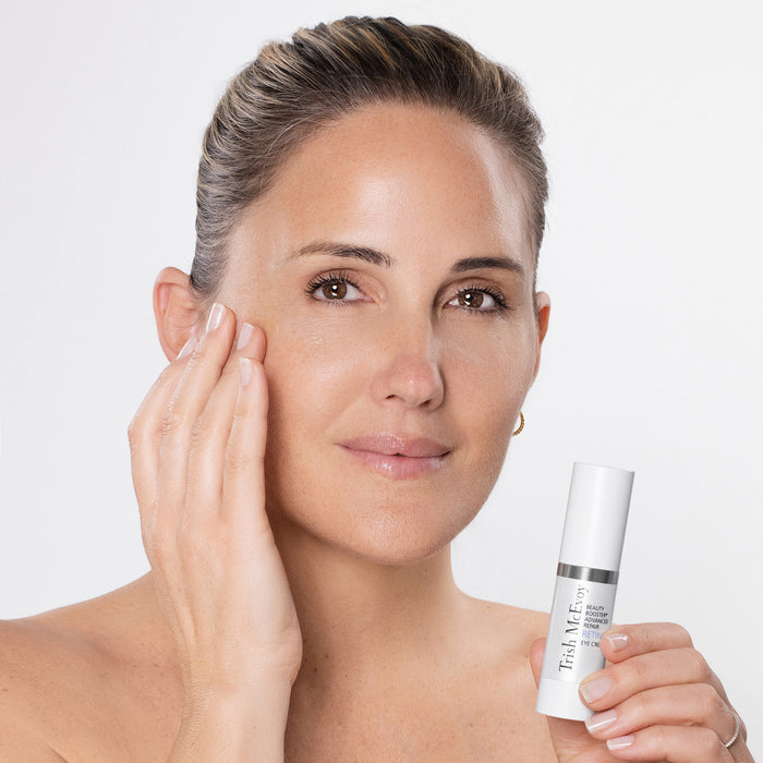 Woman holding a skincare product with a plain background