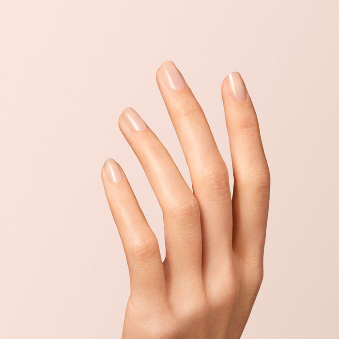 A close-up of a hand with neatly manicured nails, painted in Manucurist's Beige gel polish, against a soft beige background.