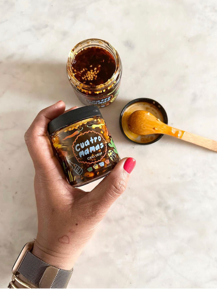 Chili crisp jar in hand, open jar with spoon on table