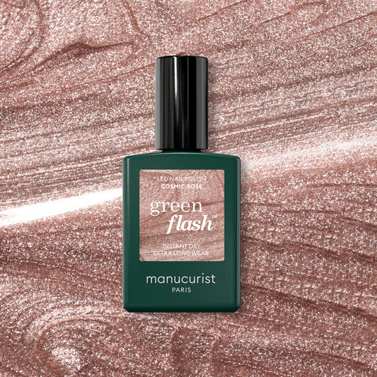 A bottle of Manucurist Cosmic Rose nail polish sits on a sparkling, rose-pink background that perfectly complements the iridescent pink shade.