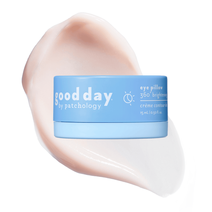 A light blue cosmetic jar labeled 'good day eye pillow 360° brightening' centered over a large pale pink cream smear on a solid green background.