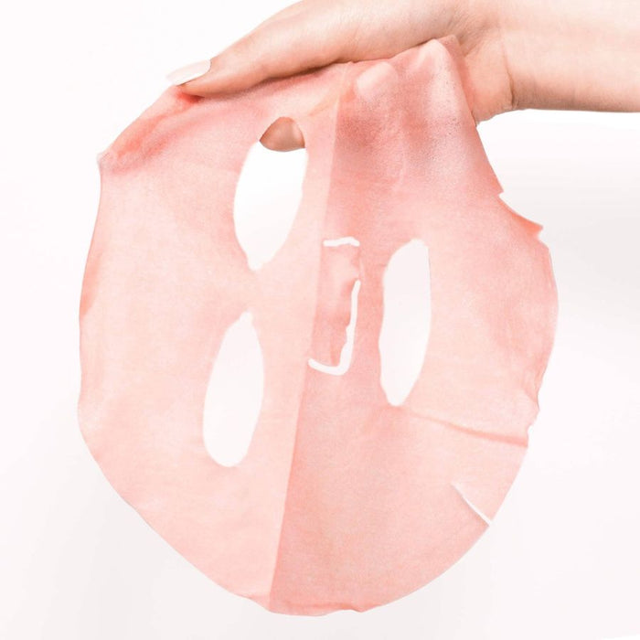 Hand holding pink sheet face mask with cutouts, hydrating skincare sheet mask ready to apply