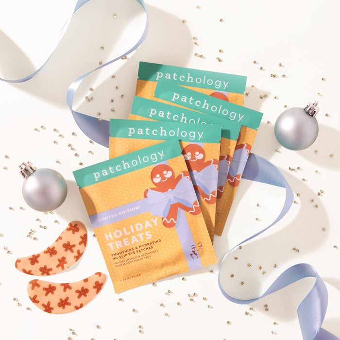 holiday-themed skincare product packaging with ribbons and ornaments on a white background