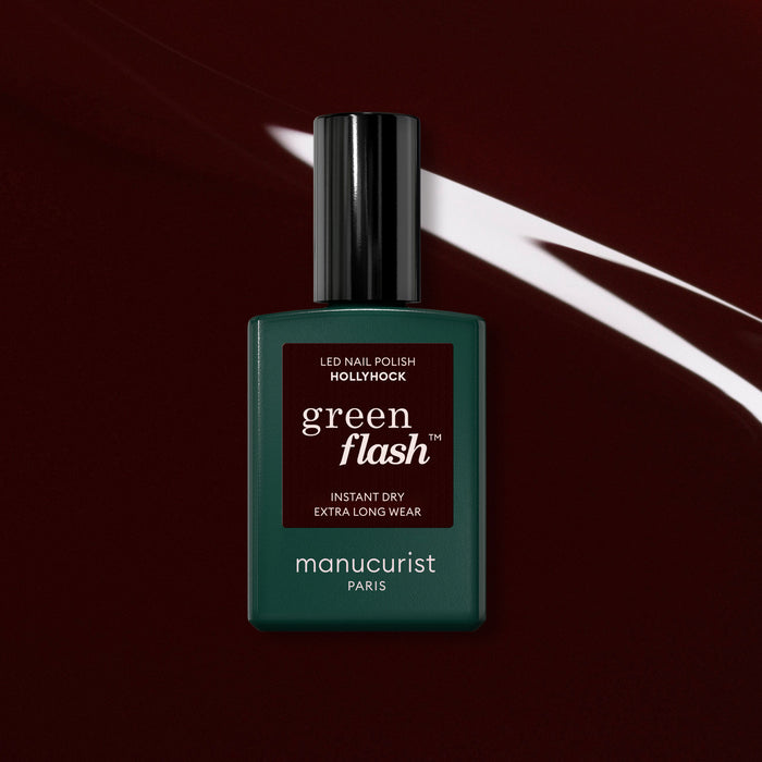 Manucurist's Hollyhock gel polish stands out against a dark burgundy backdrop with a streak of white light, showcasing the stunning black-red hue of this Green Flash collection shade.
