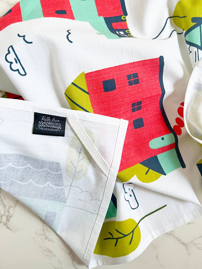 Illustrated abstract homes on The Coin Laundry kitchen towel featuring houses and cityscape design in vibrant colors.