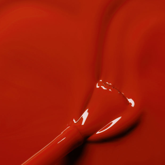 A close-up of a brush dipped in Manucurist's Indian Summer, a glossy brick red gel polish, with smooth and shiny brick red color spread across the surface.