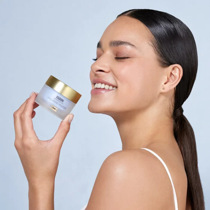 ISDIN Isdinceutics Hyaluronic Moisture jar held beside a smiling woman