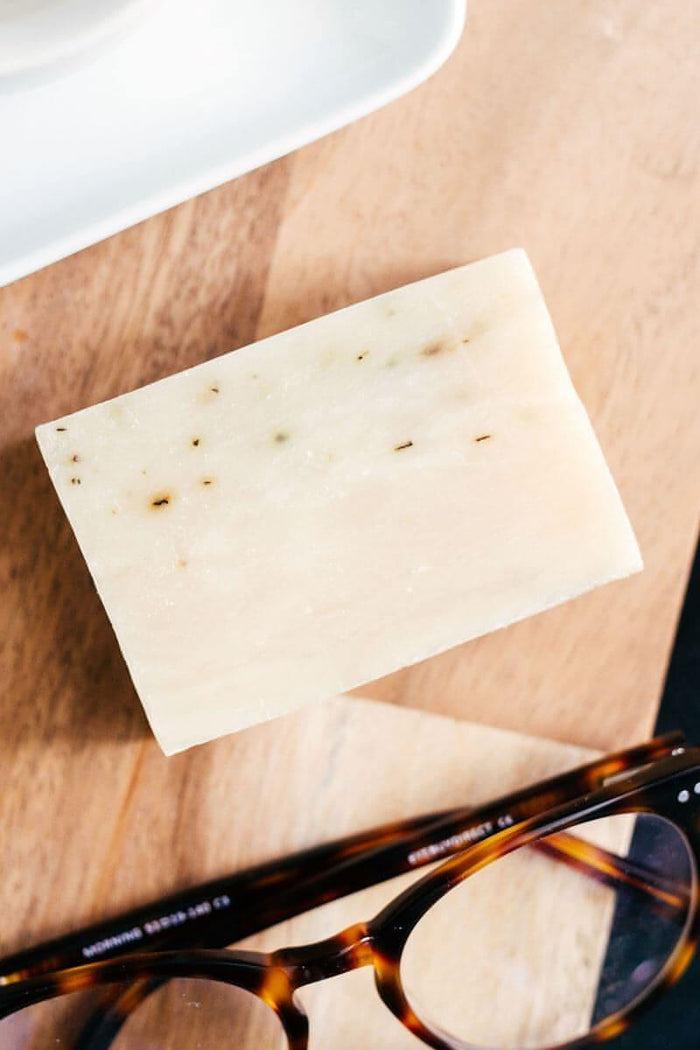 natural soap bar on wooden surface near eyeglasses