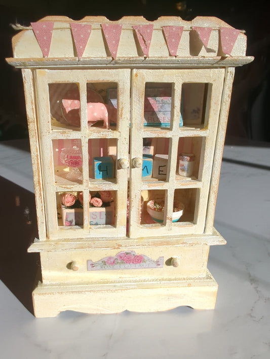 Miniature pink and white hutch scene with tiny furniture, accessories, and detailed decor from Detail In Miniature.