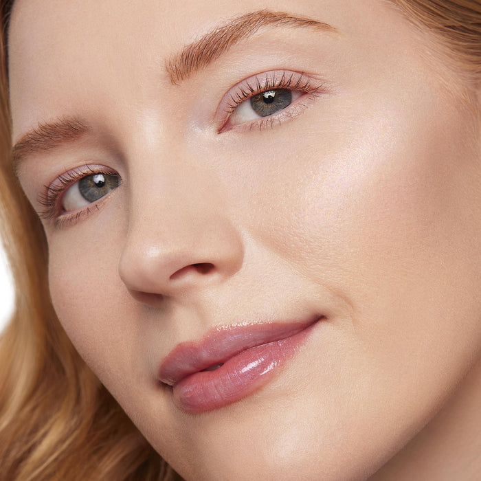 Softly lit cheekbone catching light, showcasing ColourPop Liquid Highlighter in Mother Gothel, a liquid highlighter with a pearly iridescent glow applied on light skin in a close-up beauty shot with a dewy, glassy finish.