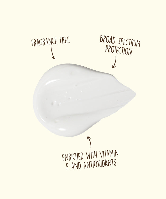 White cream smear on a light background with text indicating it is fragrance free, offers broad spectrum protection, and is enriched with vitamin E and antioxidants.