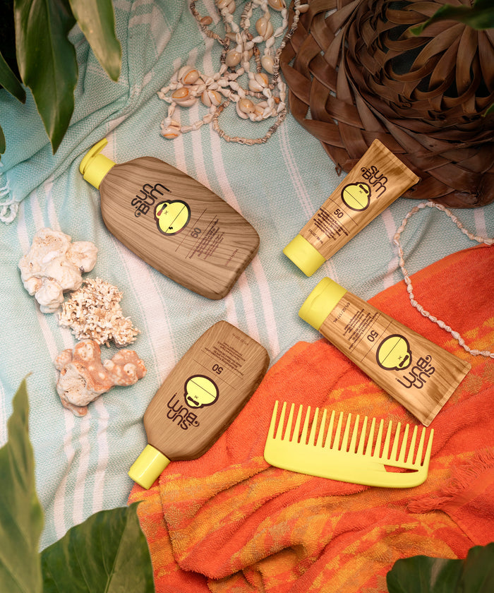 Original SPF 50 Sunscreen Lotion by Sun Bum on a beach towel with seashells, an orange scarf, and a yellow comb, Sun Bum,