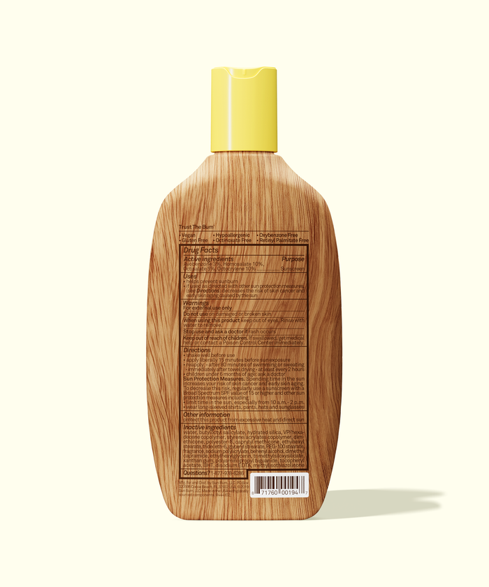 Back view of Sun Bum Original SPF 50 Sunscreen Lotion bottle with wooden texture and yellow cap against light background