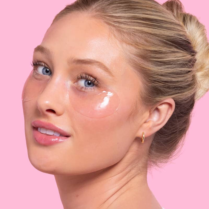 Woman with under-eye patches on a pink background