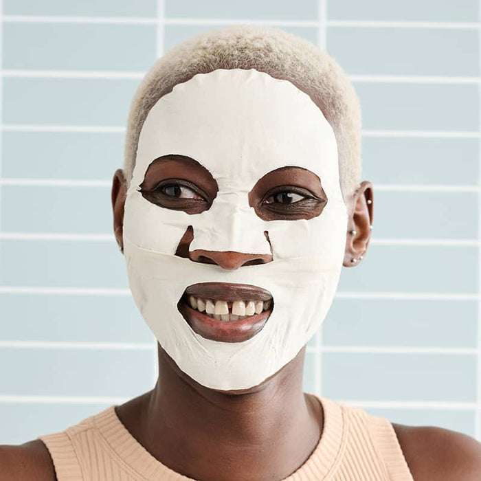 Woman wearing Patchology Mudmask Smooth smiling against tiled background, hydrating facial skincare treatment