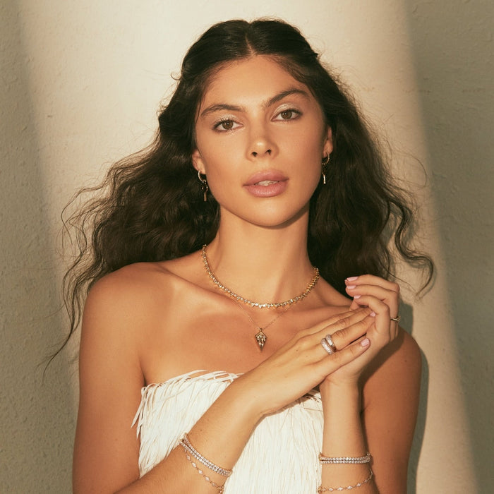 Gold-tone teardrop tennis necklace with clear teardrop stones, front on model.