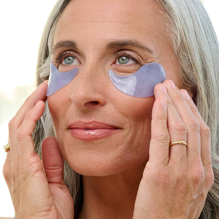 Woman applying Patchology On Ice eye gel with hands, smoothing hydrating eye treatment on mature skin