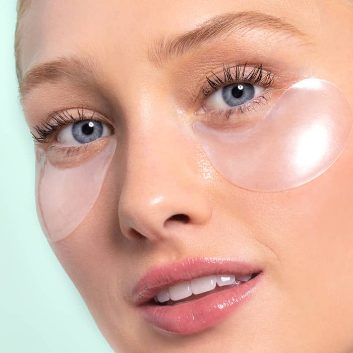 Close-up of a person wearing eye patches on a light green background