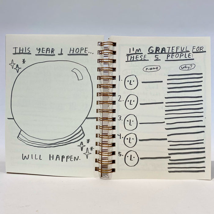 Open 12 month planner pages with hand-drawn text and icons; spiral binding visible
